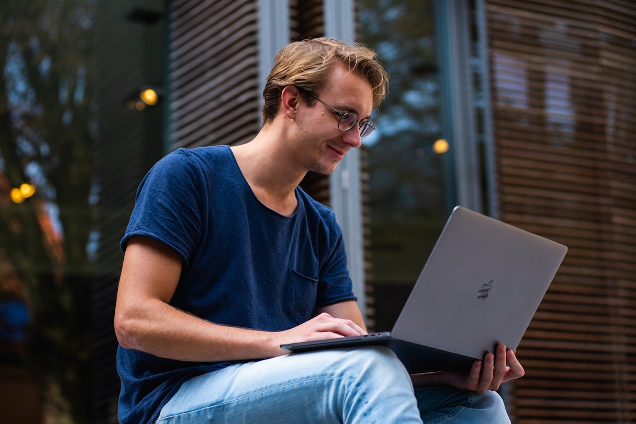 our-story A young man sitting outdoors in Leiden, Netherlands, working on a laptop.