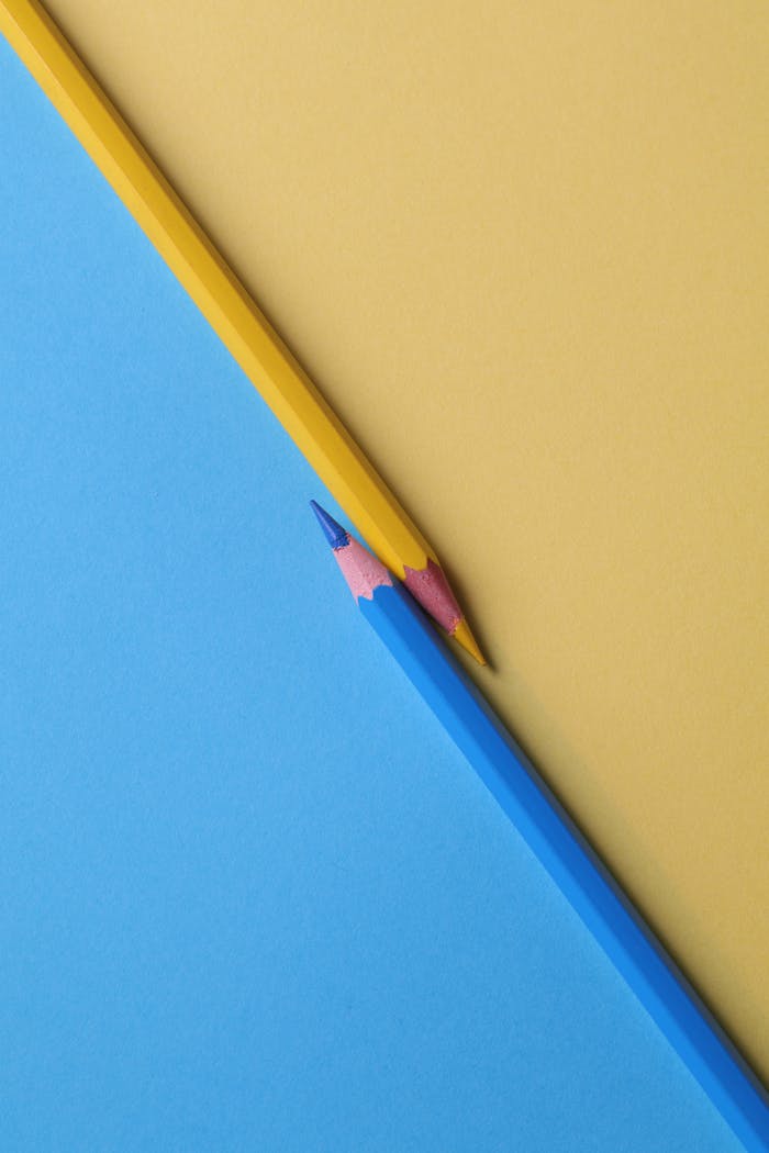 about-us Close-up of vibrant yellow and blue colored pencils on contrasting paper backgrounds.
